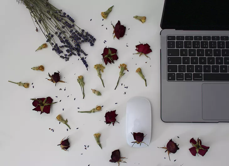 laptop on desk with scattered flowers