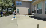 Concrete patio construction in San Antonio, TX with workers pouring cement and smoothing the surface.